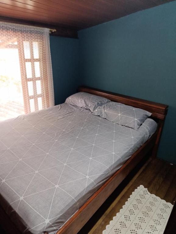 a bed in a blue room with a window at pousada nosso cantinho in Paranaguá
