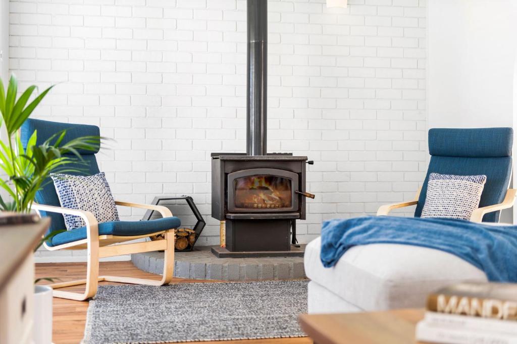 a living room with a fireplace and two chairs at Southcoast Haven in Shoalhaven Heads