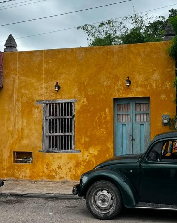 a green car parked in front of a yellow building at Charming Yellow Colonial House in the Downtown in Valladolid