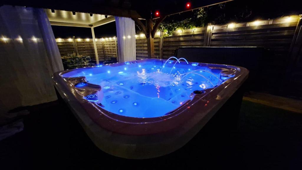 a jacuzzi tub with blue water at night at Les Trois Palmiers - Jardin & Spa privatifs in Les Bréviaires