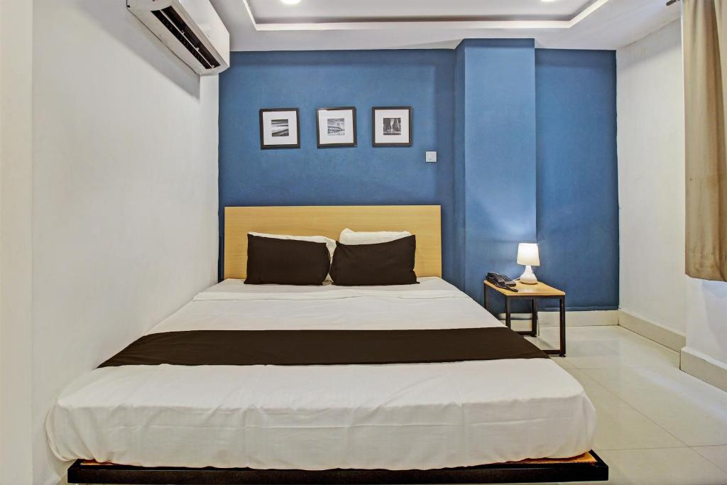 a bedroom with a bed with a blue wall at Hotel O Qualia Miyapur in Hyderabad