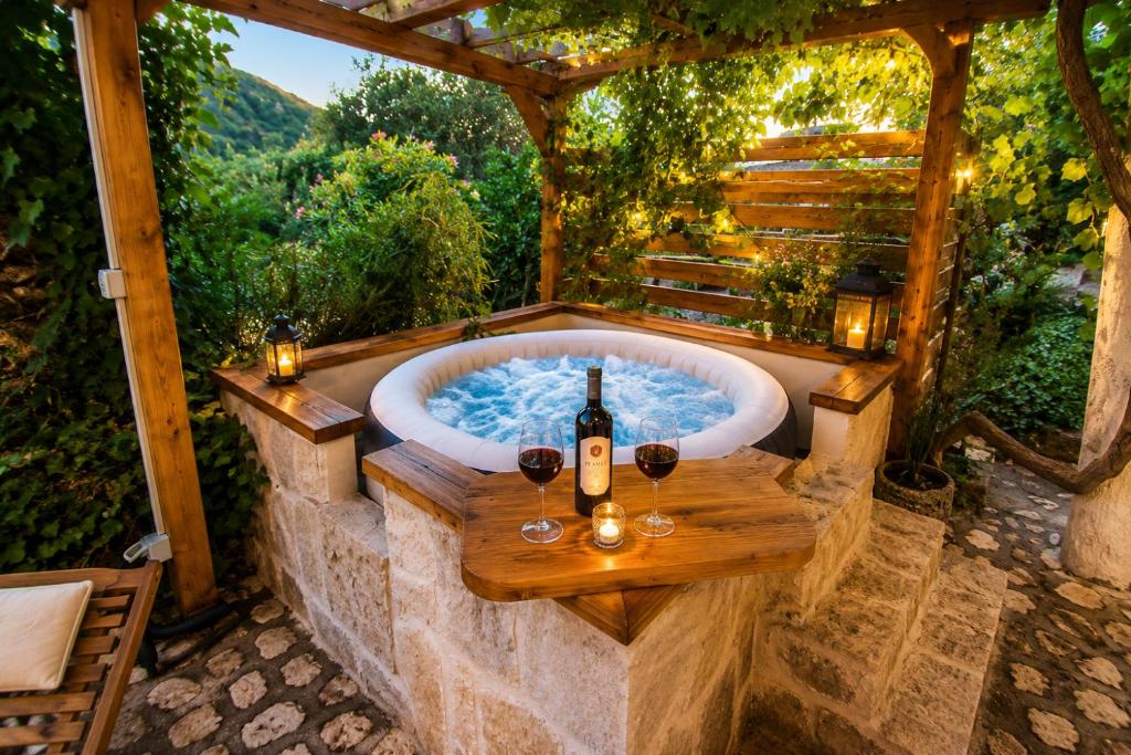 a jacuzzi tub with two glasses of wine at Rustic Garden & Jacuzzi Retreat in Vis