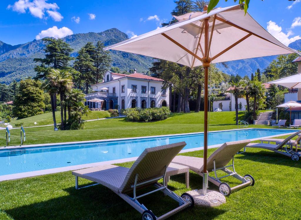 a pool with chairs and an umbrella next to a house at Villa Lario Resort Mandello in Mandello del Lario
