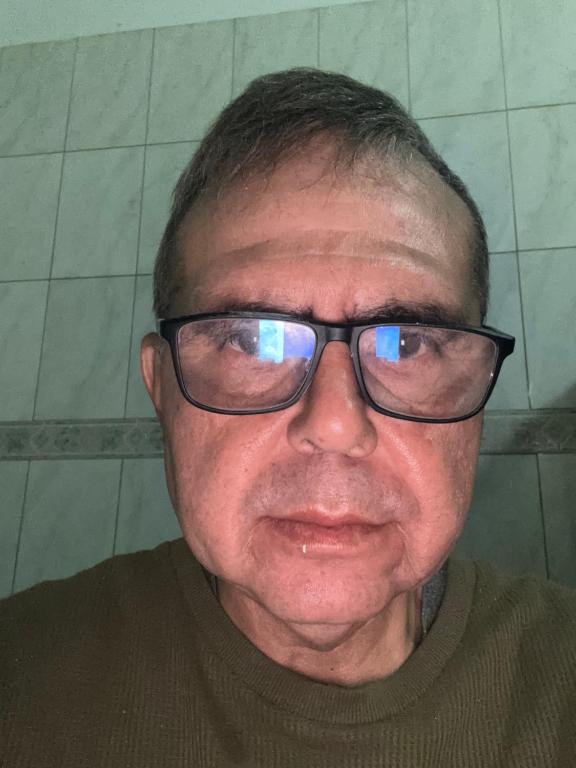 a man wearing glasses is smiling at the camera at Apartamento in Ribeirão Preto
