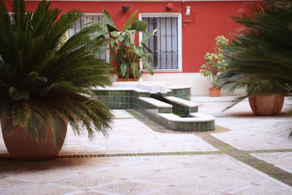 a courtyard with benches and palm trees in front of a building at Apartamento Judería Lirio alto in Seville