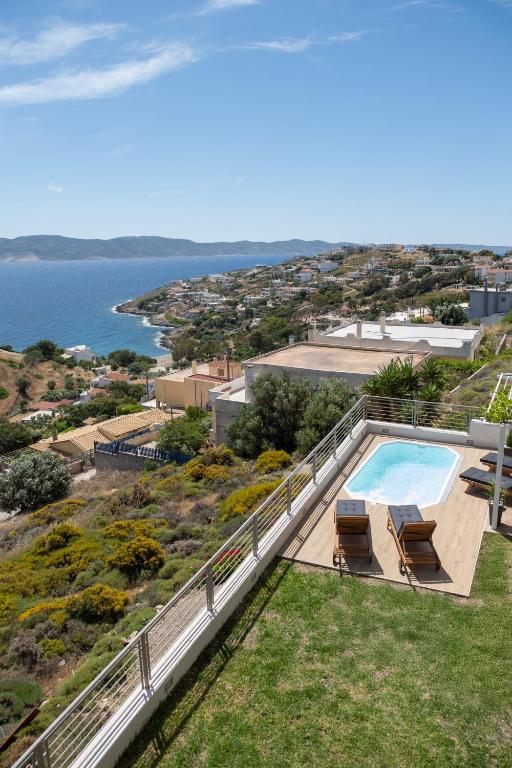 an overhead view of a swimming pool with chairs and the ocean at Oasis Sea view suit in Agia Marina Mikrolimanou