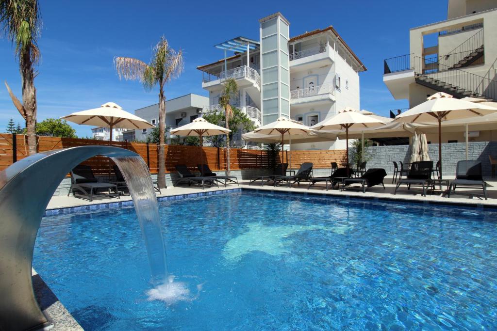 a swimming pool with a fountain in front of a building at Hotel Villa Kapo Pool & Bar in Ksamil
