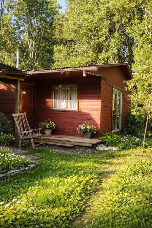 a wooden cabin with a chair and a window at Puñañas descanso y experiencias in Vilcún