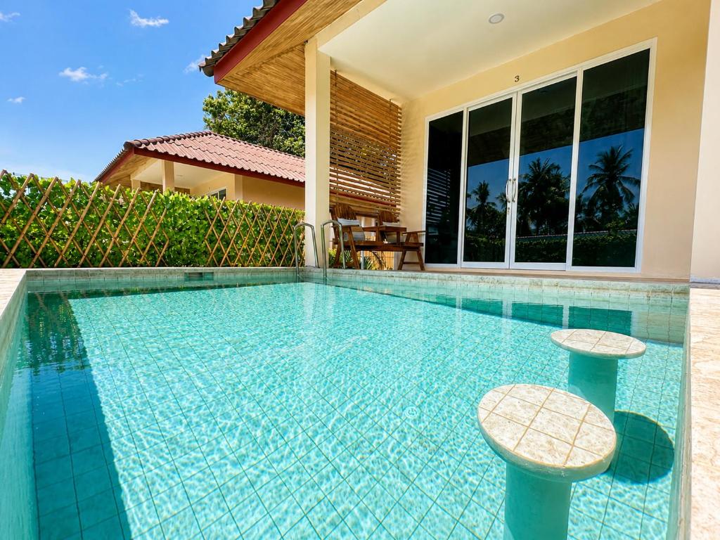 a swimming pool with two stools in front of a house at Oh'lala Pool Cottages in Ban Tai