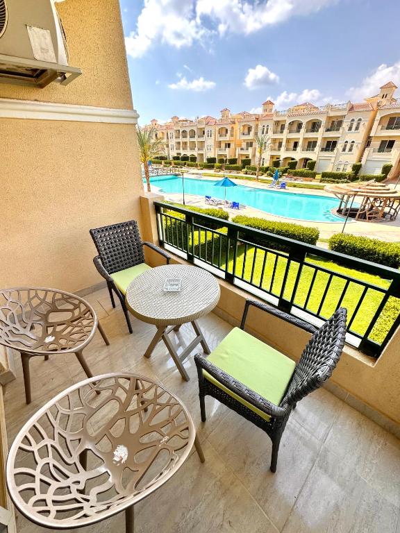 a balcony with tables and chairs and a pool at Lasirena Palm Beach Sokhna Chalet in Ain Sokhna