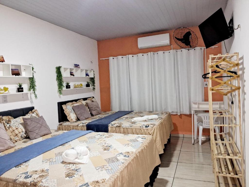 a room with two beds and a desk in it at Hospedagem Aconchego Do Lar in Barreirinhas