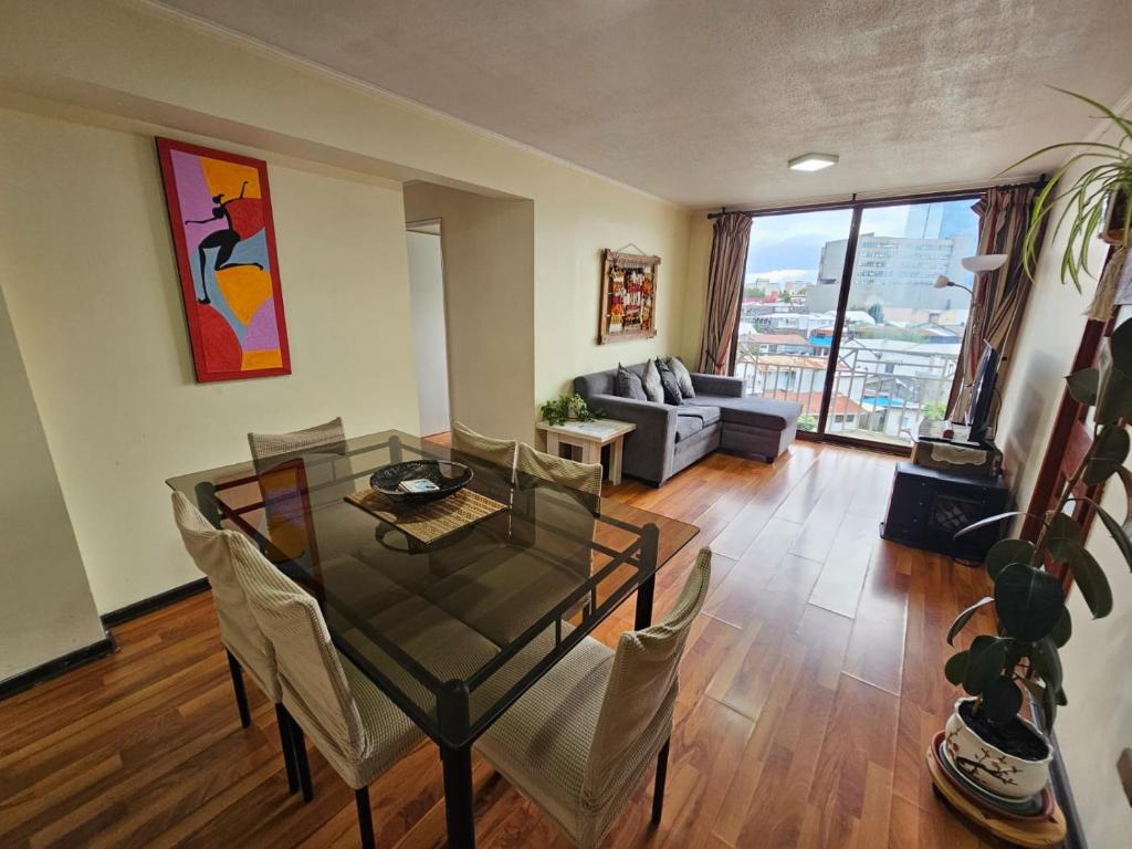a living room with a glass table and chairs at Acogedor y amplio departamento central in Temuco