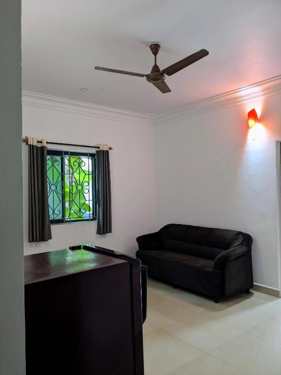 a living room with a couch and a ceiling fan at shivkrupa Guest house in Arambol