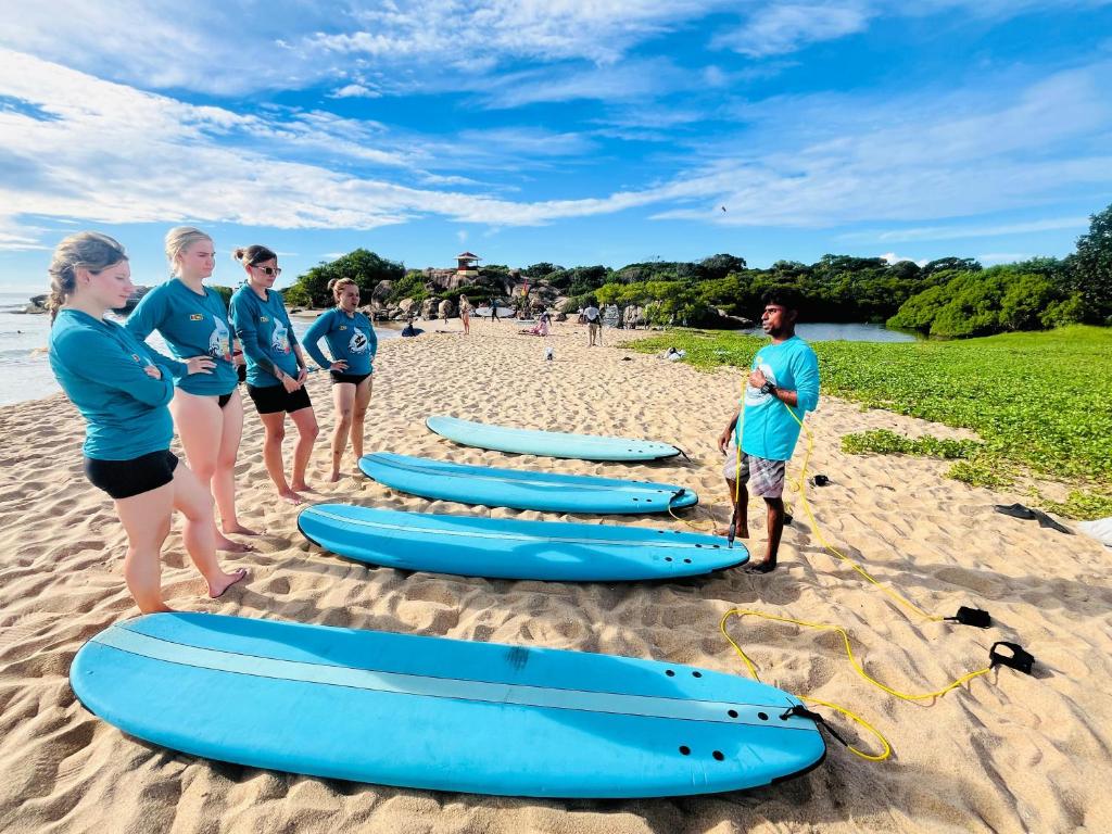 a group of people standing next to surfboards on a beach at saha surf camp in Arugam Bay