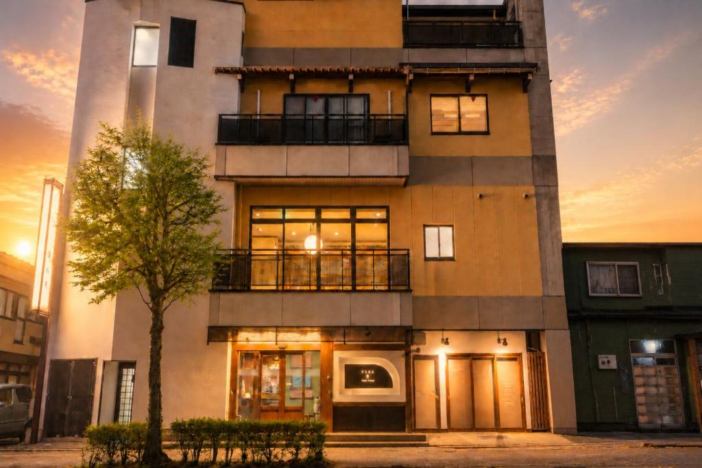 a building with a tree in front of it at Guest House Ouka in Takayama