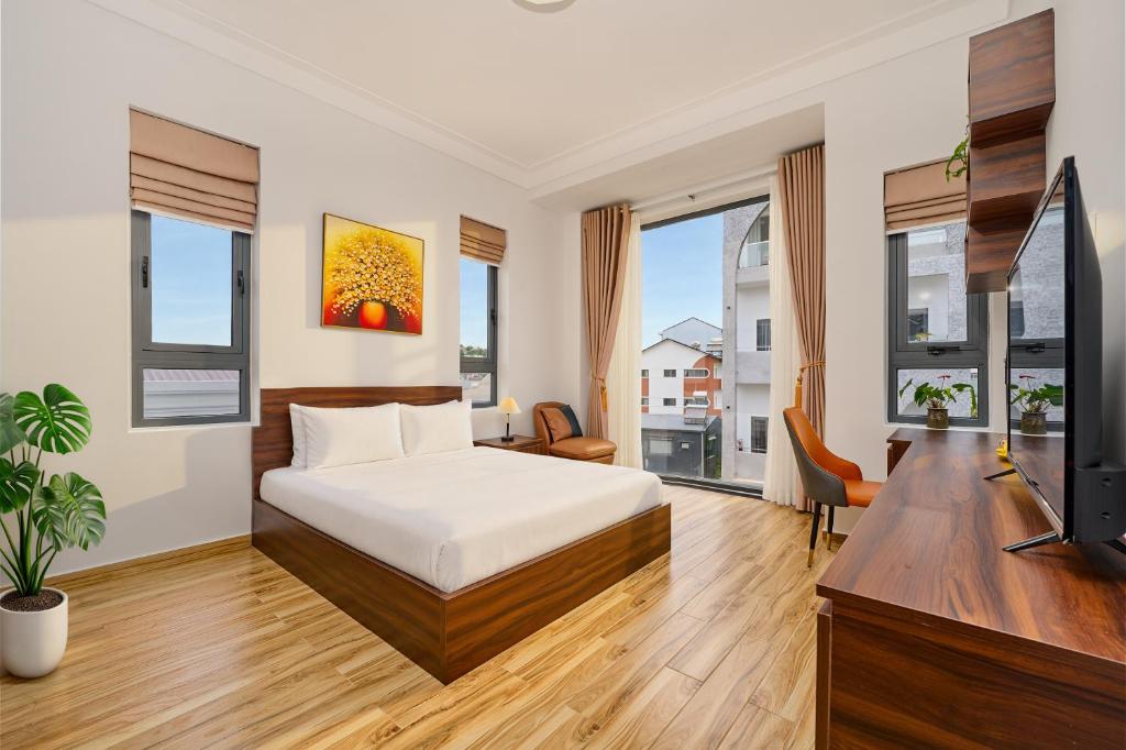a bedroom with a bed and a tv and windows at KP Villa Dalat in Da Lat