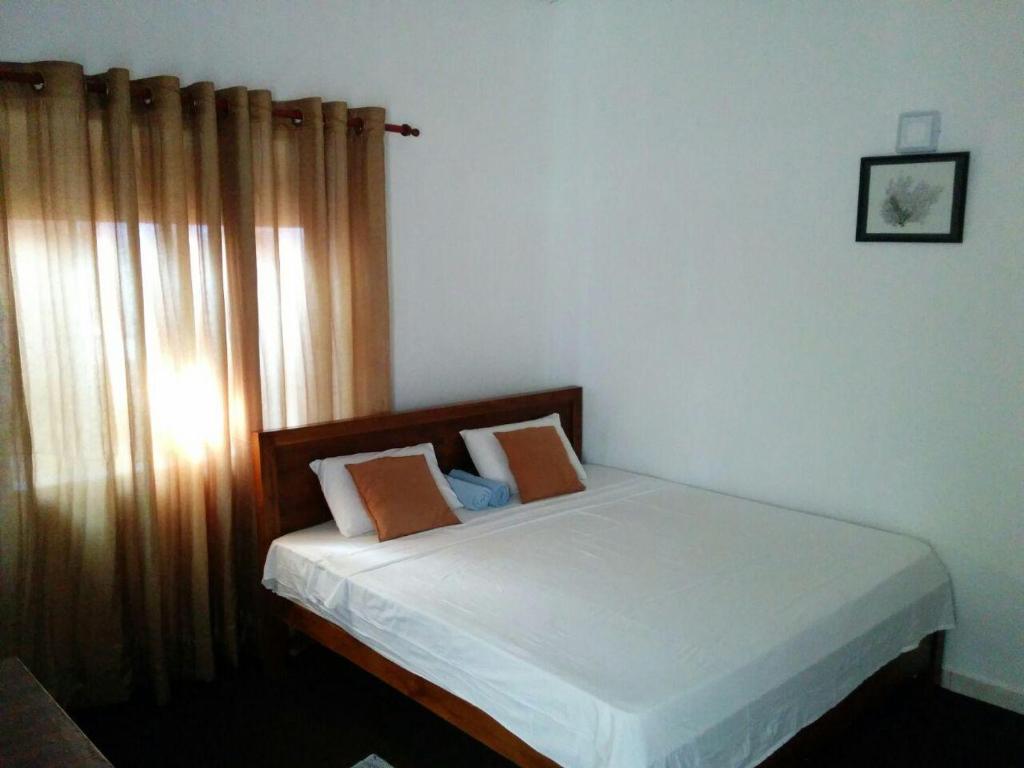 a bedroom with a bed with white sheets and a window at Villa Two Residence in Mount Lavinia