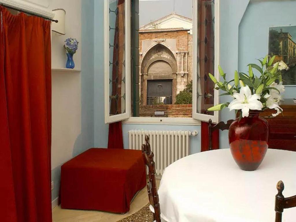 una habitación con un jarrón sobre una mesa y una ventana en Cà Tornielli apartment, en Venecia