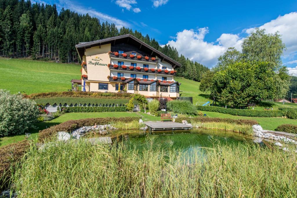 un hôtel avec un étang en face d'un bâtiment dans l'établissement Berghotel Presslauer, à Jenig