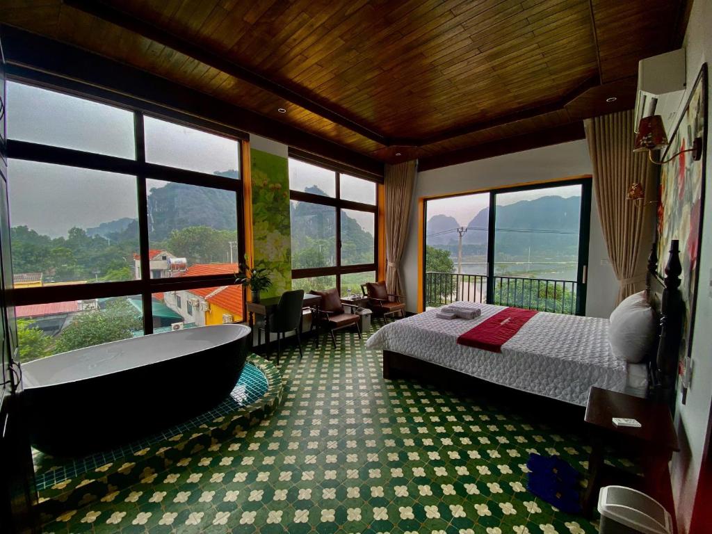 a bedroom with a bed and a bath tub and windows at Tam Cốc mountain view Villa in Ninh Binh