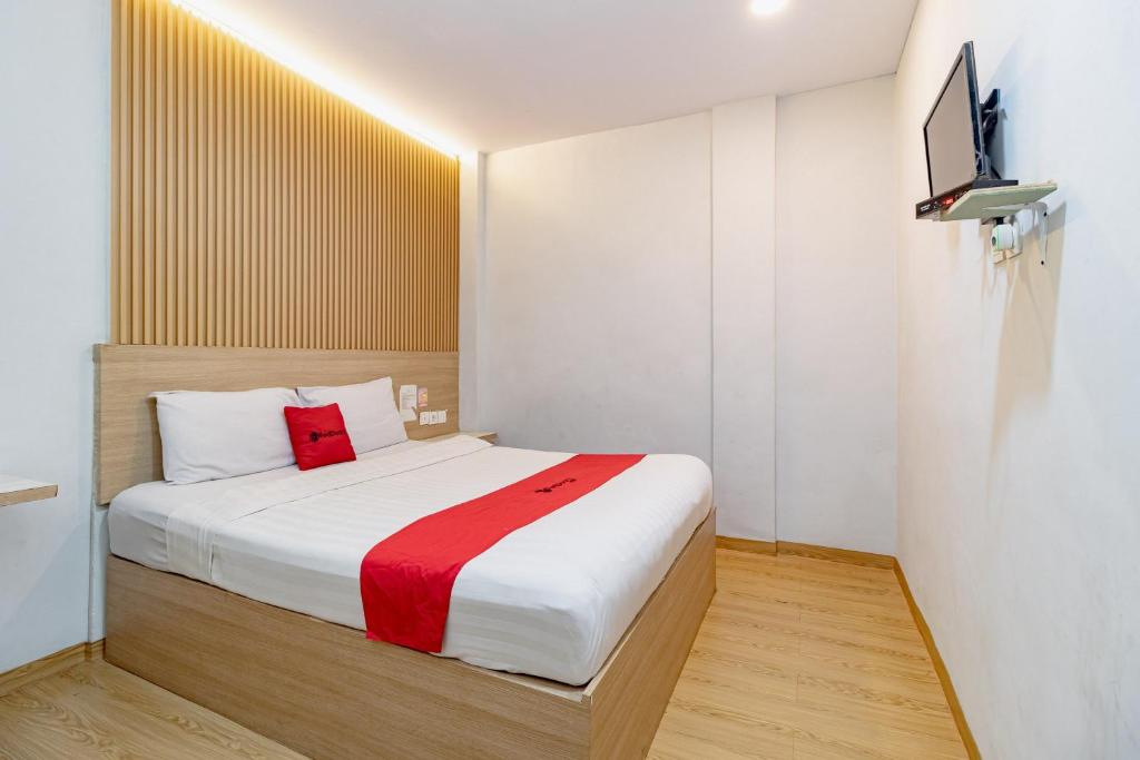 a bedroom with a bed and a tv on a wall at RedDoorz Plus at Suba Hotel Tanjung Duren in Jakarta