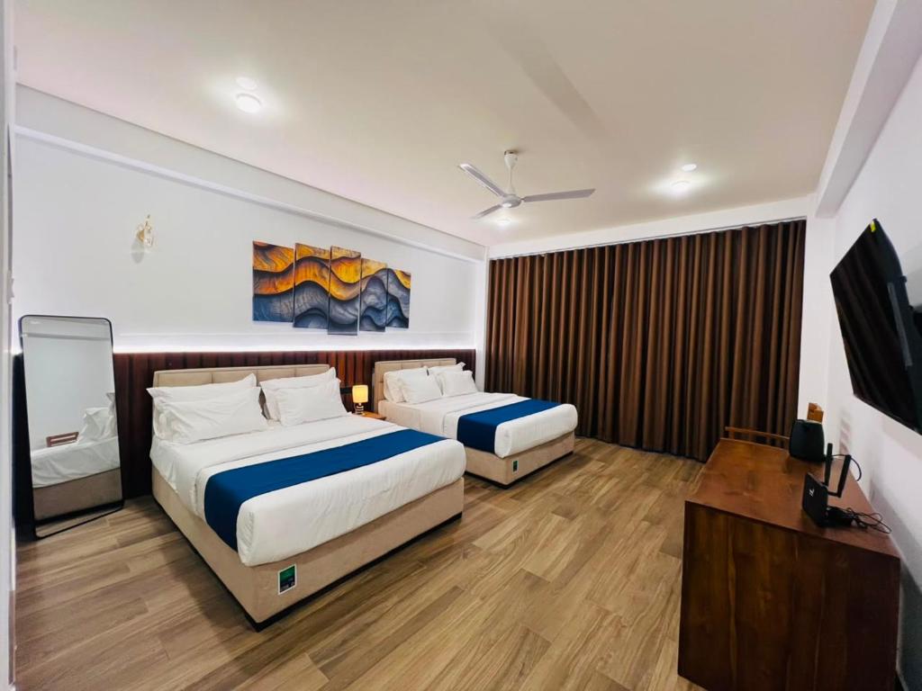 a bedroom with two beds and a flat screen tv at Heda Retreat in Aluthgama