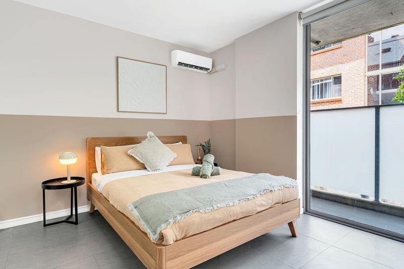 a bedroom with a bed and a large window at 4B Relaxing Abnb Studio With Balcony, Near Marketplace And Train in Bankstown