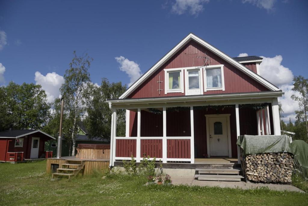 una casa roja con porche y patio en Puoltikasvaara 3, en Puoltikasvaara