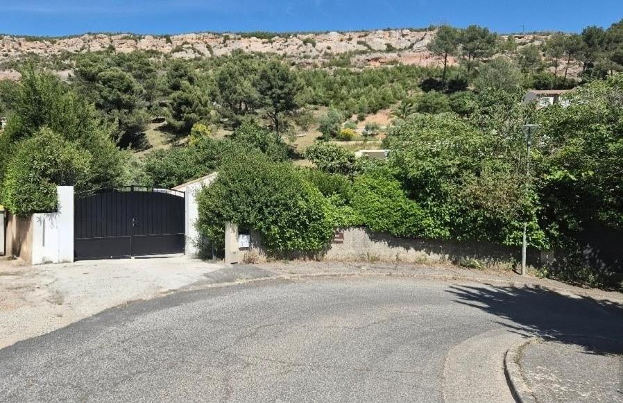 an empty road next to a fence and trees at La maison du soleil in Vitrolles