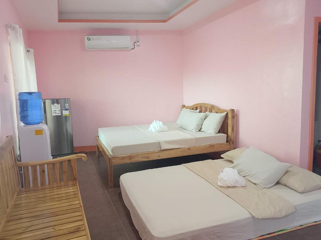 a room with two beds and a refrigerator in it at Tellos Beach House in Siquijor