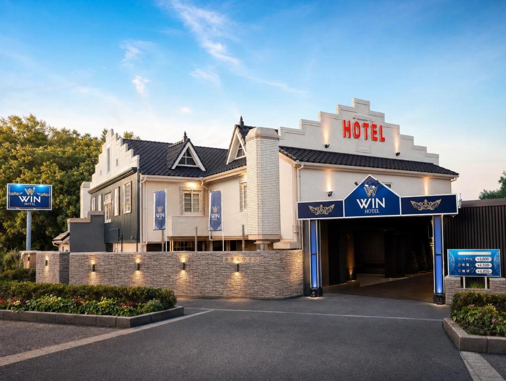 a hotel building with a hotel sign in front of it at Hotel WIN in Fukaya