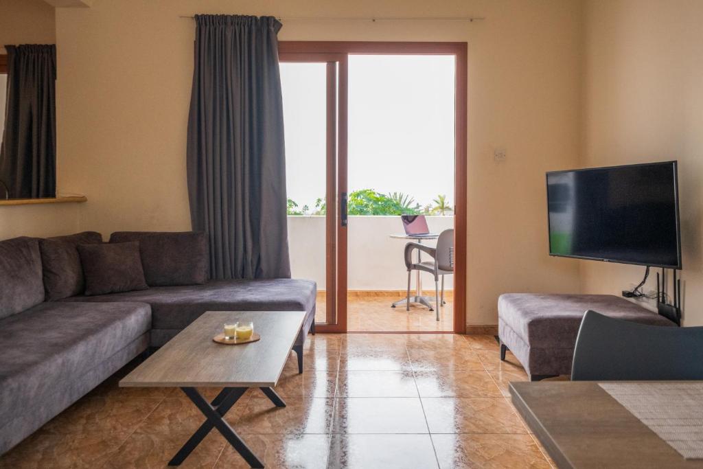 a living room with a couch and a tv at Sunset Sea View Retreat with pool in Kissonerga