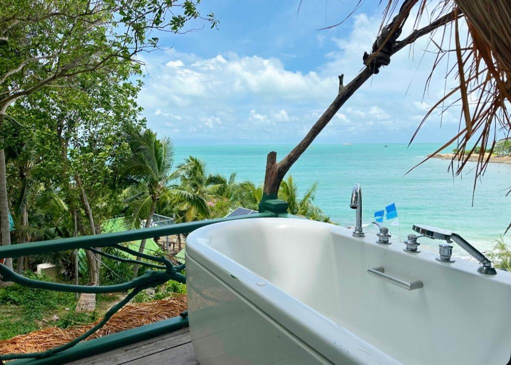 a bathroom with a bath tub and the ocean at Benny Seaview house in Ao Phutsa