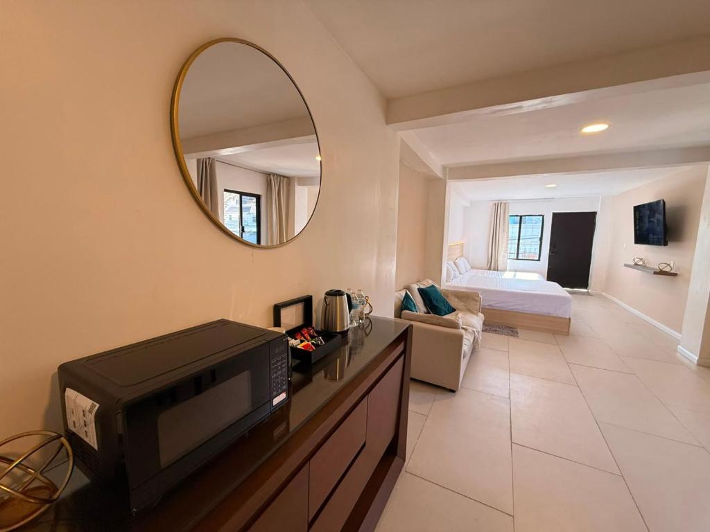 a living room with a tv and a bed and a mirror at RA Suites in Tijuana