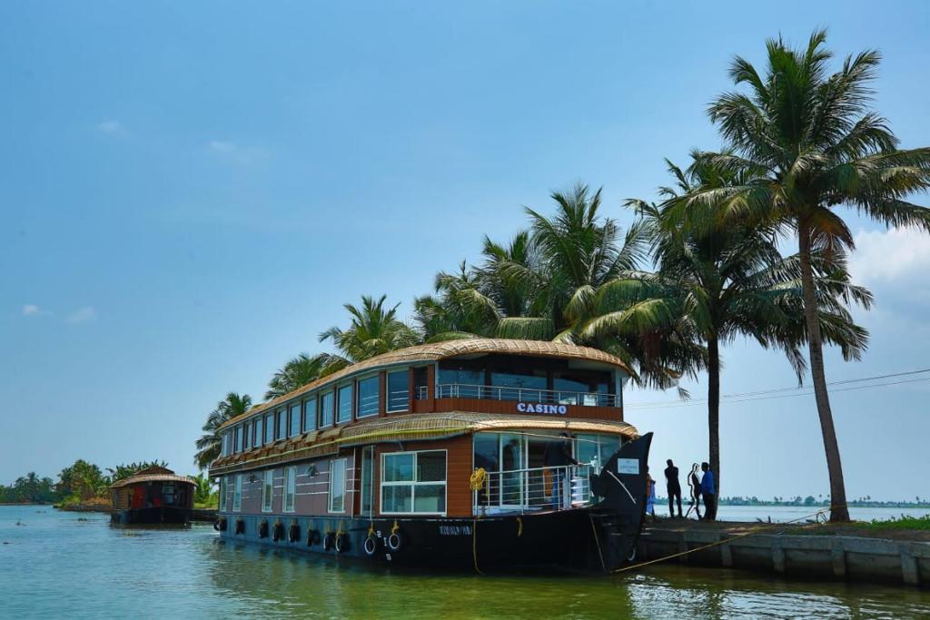 a house boat on the water with palm trees at Hills & Cruise Luxury Houseboats in Alleppey