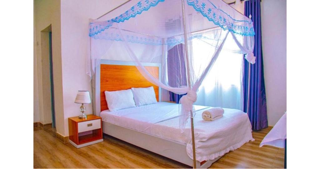 a bedroom with a canopy bed with a window at Breeze House Hotel in Kigali