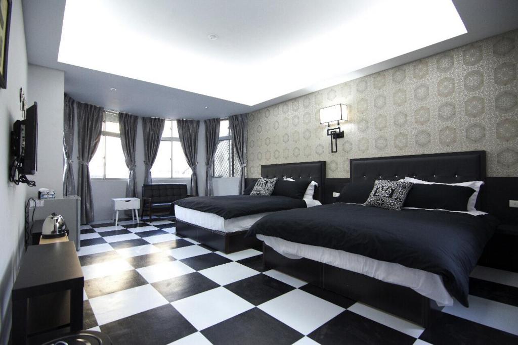 a bedroom with two beds and a checkered floor at Chao Daily Rent in Tainan