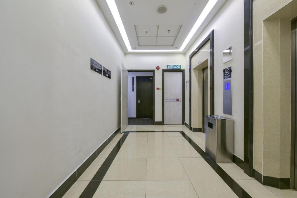 A bright tiled corridor leads to elevators and an exit door.