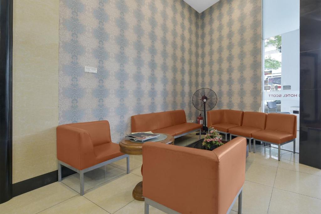 A small waiting lounge with orange upholstered chairs around a coffee table.