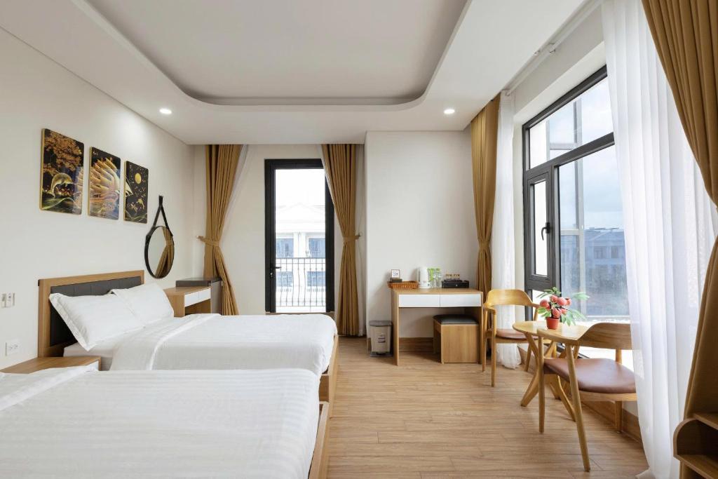 a hotel room with two beds and a desk at Thai Thinh Hotel Grand World in Phú Quốc