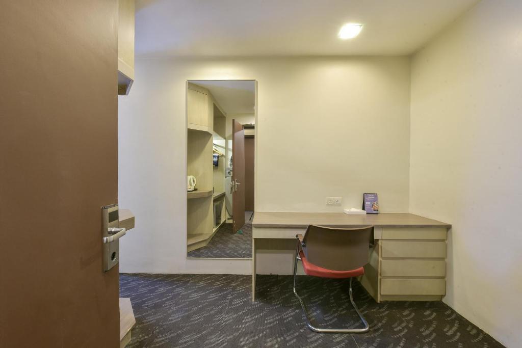 A compact in-room work area with a built-in desk, drawers, chair, and full-length mirror.