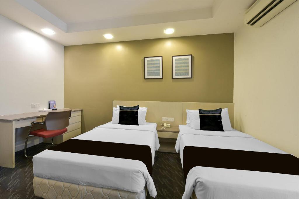 A twin room with two beds, a narrow desk and wall-mounted air conditioning.