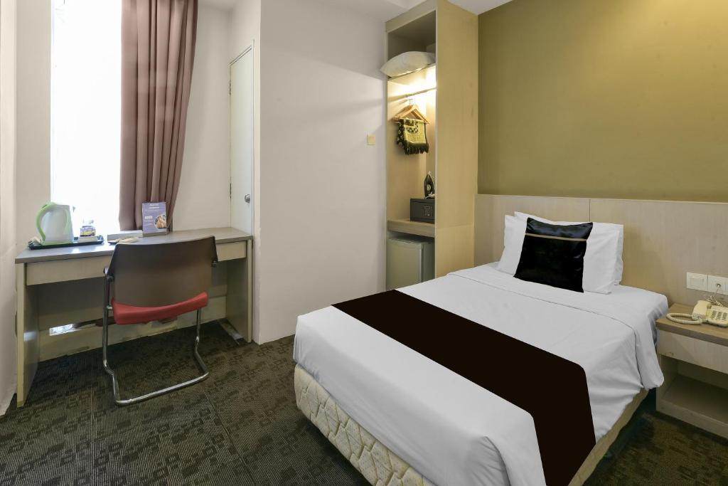 A single-bed room with a window-side desk, kettle and small refreshment area.