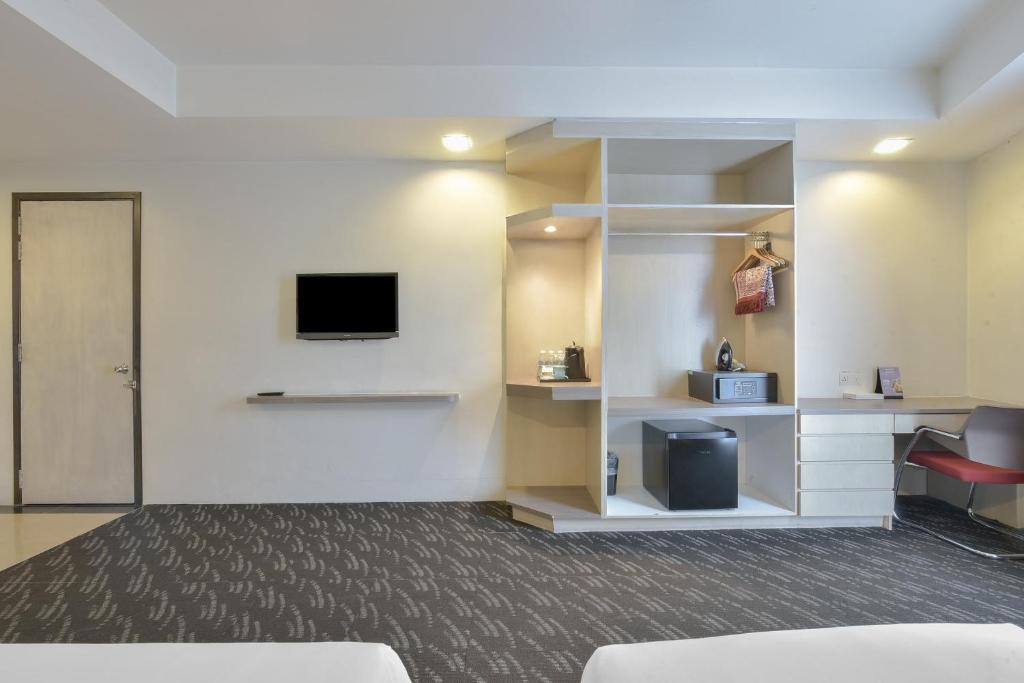 A room view showing the TV wall, open shelving, minibar and desk area.