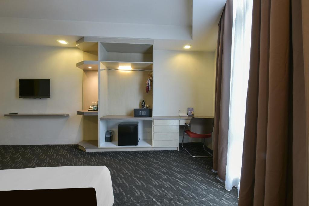 A room corner with a desk beside the curtained window and built-in storage.