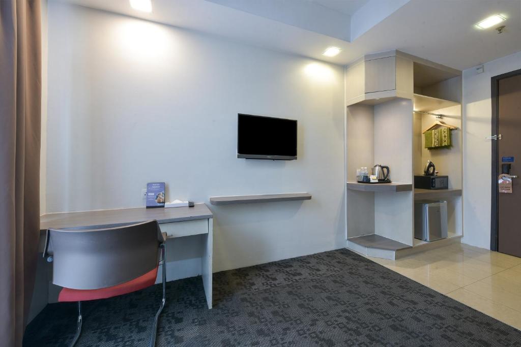 A small in-room work area beside a wall-mounted television and tea station.