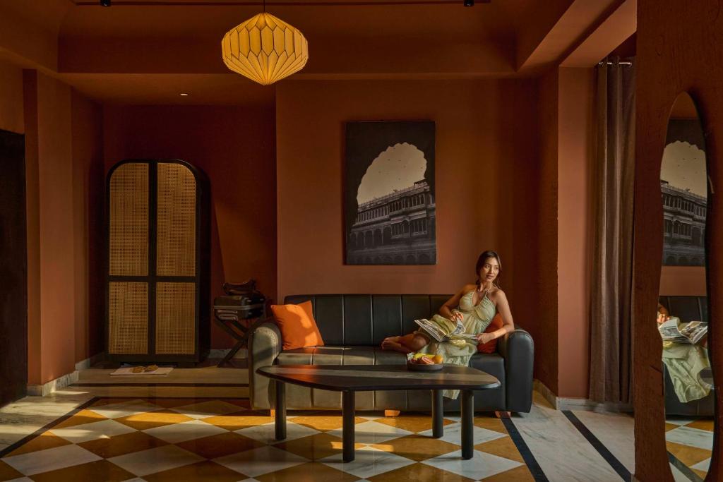 a woman sitting on a couch in a living room at Minimalist - Lake Pichola Edit in Udaipur