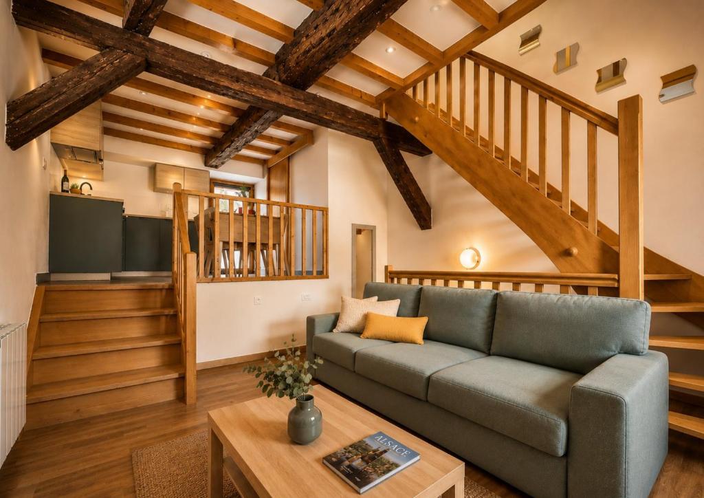 a living room with a couch and a staircase at L'Atypique in Eguisheim