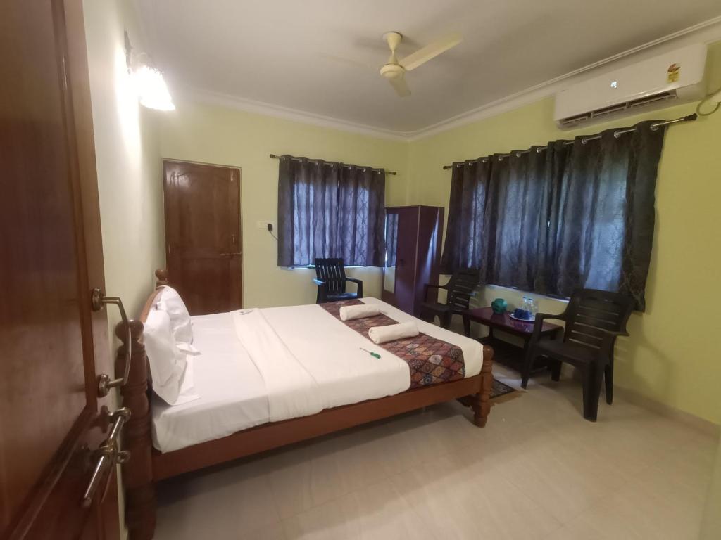 a bedroom with a bed and a table and chairs at Home Dwarka in Arambol