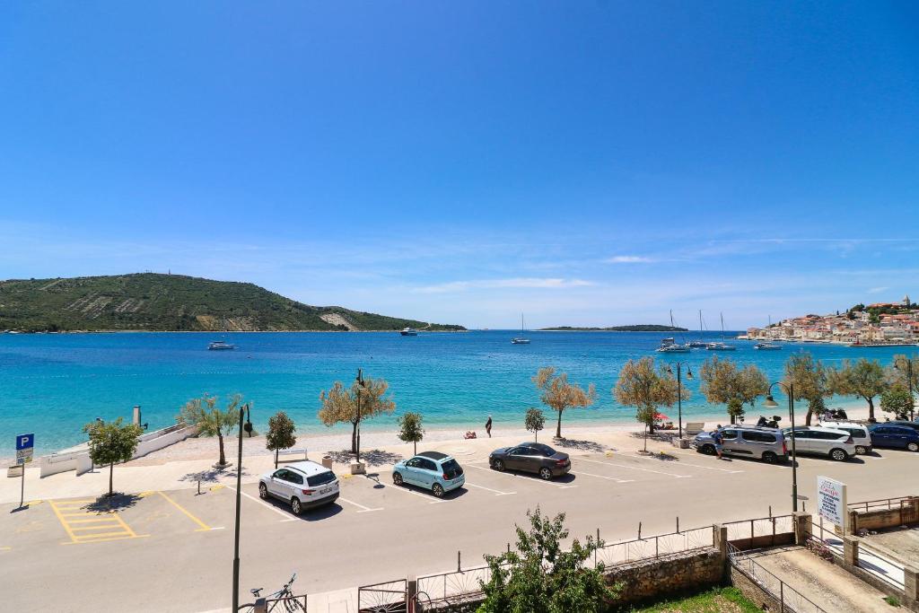 a parking lot next to the ocean with cars parked at D&J Apartments in Primošten